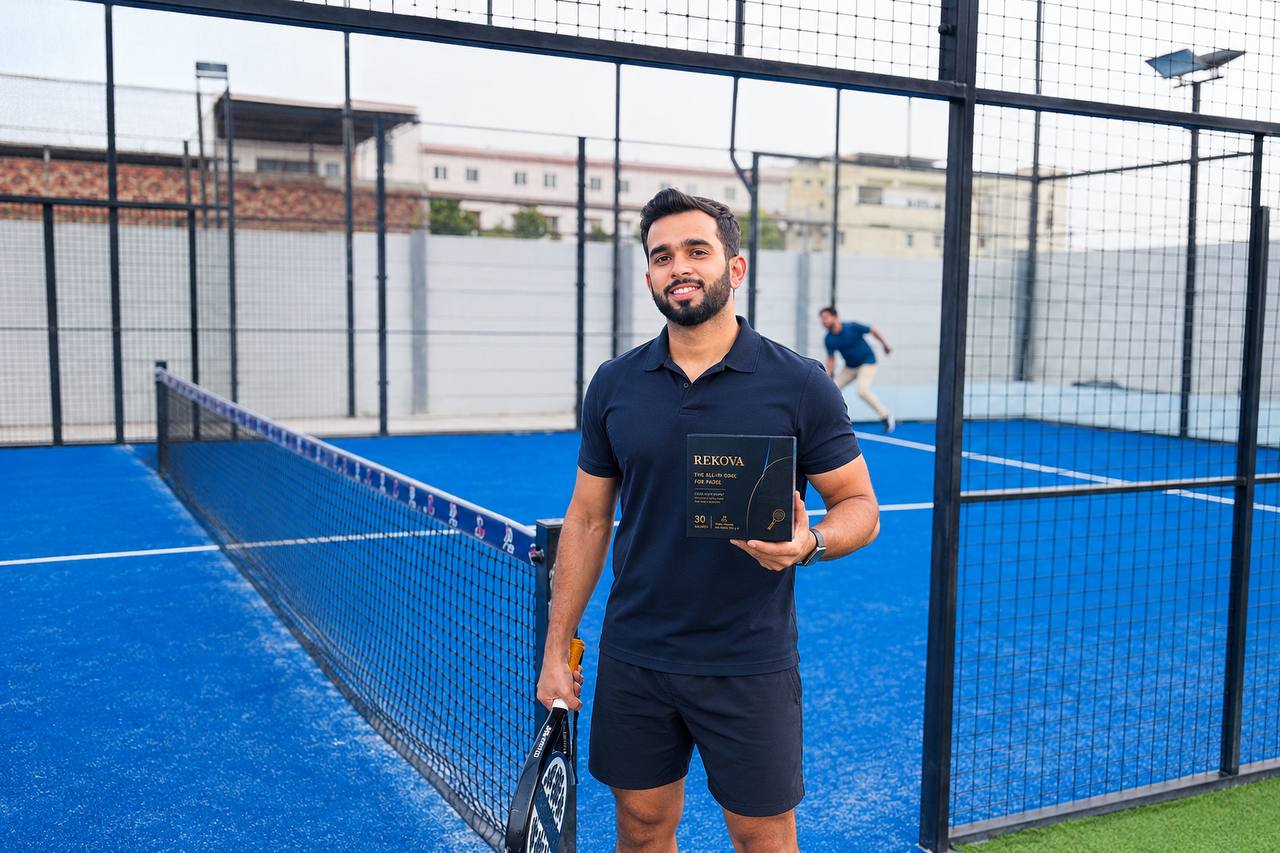 Padel player holding a Rekova box on a blue padel court