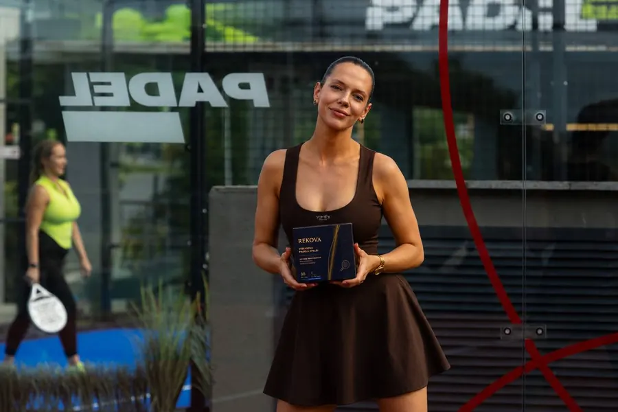 Padel player holding a Rekova box at a padel club entrance