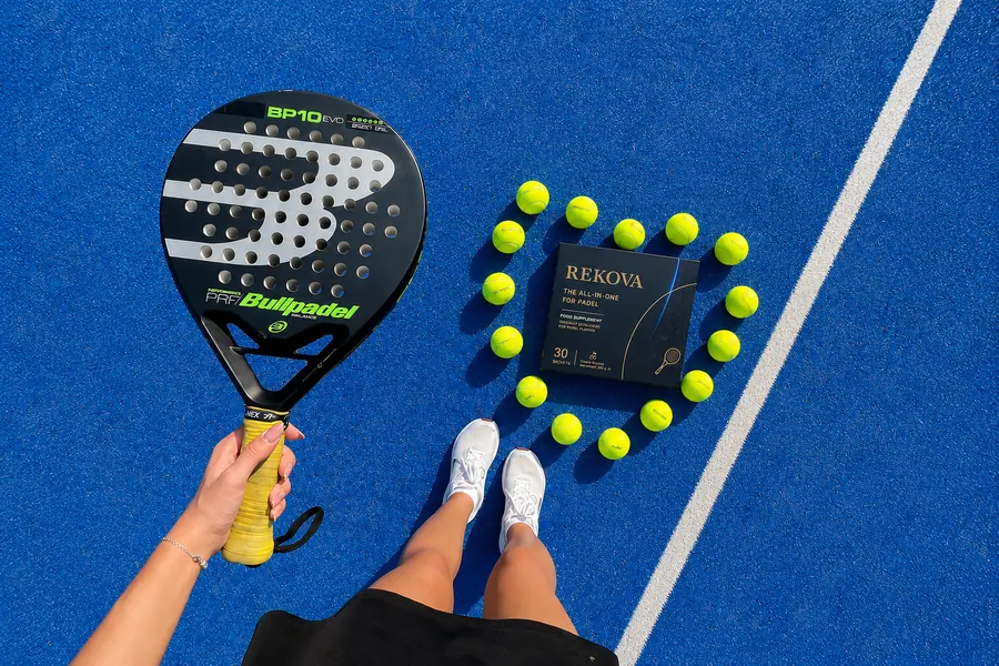 Rekova box surrounded by padel balls on a blue court